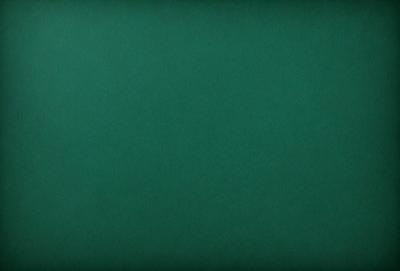 The primary subject of the image is a large, green, textured surface. The setting is a dark room, and the visual style is a close-up of the green surface. The colors and mood of the image are predominantly dark and moody, with the green surface being the main focus.