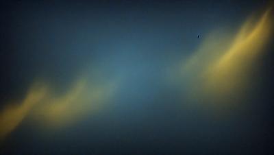 The primary subject of the image is a blue sky with clouds. The setting is a dark, cloudy sky, and the visual style is a photo. The dominant colors are blue and gray, creating a moody atmosphere.