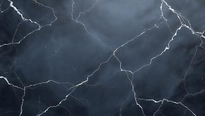 The primary subject of the image is a close-up of a cracked, textured surface, possibly a marble or stone wall. The setting is a dark, cloudy sky, which creates a moody atmosphere. The visual style is a black and white photo, giving the image a classic and timeless feel. The dominant colors are black and white, with the cracked surface adding a touch of gray and brown.