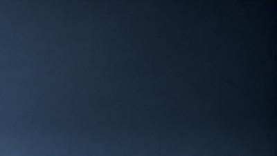 The primary subject of the image is a dark blue sky. The setting is a vast, open space with no visible landmarks or objects. The visual style is a natural, outdoor scene. The colors and mood are predominantly dark and moody, with the blue sky being the main focus of the image.