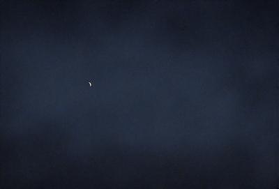 Primary subject: A moon in the sky.

Setting/background: A dark, cloudy sky.

Visual style: A photo.

Colors and mood: The image is in black and white, giving it a classic and timeless feel.