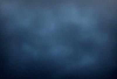 The primary subject of the image is a cloudy blue sky. The setting is an open sky, with no visible landmarks or objects. The visual style is a natural, outdoor scene. The dominant colors are blue and gray, creating a calm and serene atmosphere.