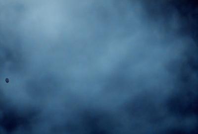 The primary subject of the image is a cloudy blue sky. The setting is a vast, open space with no visible landmarks or objects. The visual style is a natural, outdoor scene. The colors and mood are predominantly blue, creating a calm and serene atmosphere.