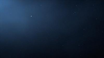 The primary subject of the image is the night sky, which is filled with stars. The setting is a dark, cloudy night, with the stars shining brightly against the black background. The visual style is a realistic representation of the night sky, with no indication of it being a photo, digital art, illustration, drawing, pattern, texture, or clipart. The colors and mood of the image are predominantly dark and serene, with the stars providing a sense of wonder and tranquility.