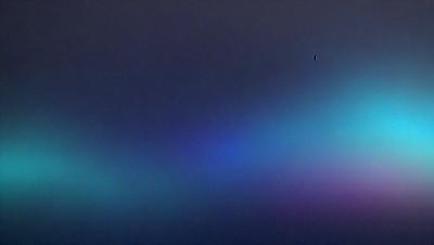 The primary subject of the image is a colorful, swirling, and vibrant pattern that resembles a rainbow. The setting is a dark, cloudy sky, which contrasts with the bright colors of the pattern. The visual style of the image is a combination of photo and digital art, creating a unique and eye-catching effect. The dominant colors in the image are a mix of blue, green, and red, giving the scene a lively and energetic atmosphere.