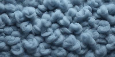 The primary subject of the image is a blue, woolly fabric. The setting is a blue background, which creates a contrast with the fabric. The visual style is a close-up of the fabric, showcasing its texture and details. The colors and mood of the image are predominantly blue, giving it a calm and serene atmosphere.