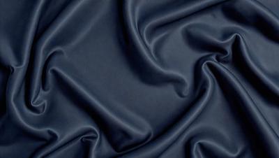 The primary subject of the image is a blue fabric, which appears to be a piece of cloth or a curtain. The setting is a dark room, and the visual style is a close-up of the fabric. The colors and mood of the image are predominantly dark and moody, with the blue fabric being the main focus.