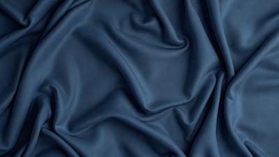 The primary subject of the image is a blue fabric, which is the main object, scene, or focus of the image. The setting or background is a dark blue cloth, and the visual style is a photo. The dominant colors and overall atmosphere are dark blue and blue, creating a calm and serene mood.