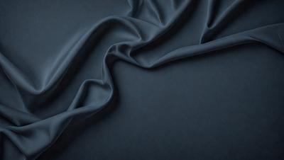The primary subject of the image is a blue fabric, which is the main object, scene, or focus of the image. The setting or background is a dark blue surface, which provides a contrasting backdrop for the fabric. The visual style of the image is a close-up of the fabric, showcasing its texture and details. The colors and mood of the image are predominantly dark and moody, with the blue fabric serving as the main source of color and visual interest.