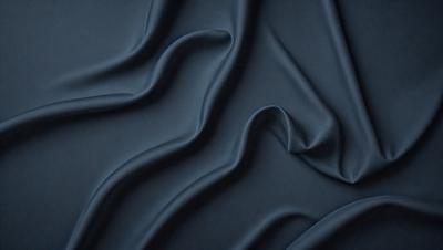 The primary subject of the image is a close-up of a blue fabric, possibly a piece of clothing or a curtain. The setting is a dark room, and the visual style appears to be a photo. The dominant colors are blue and black, creating a moody atmosphere.