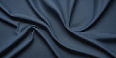 The primary subject of the image is a blue fabric, which is the main object, scene, or focus of the image. The setting or background is a dark blue cloth, and the visual style is a close-up of the fabric. The colors and mood of the image are predominantly dark blue, creating a calm and serene atmosphere.