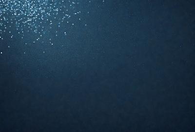The primary subject of the image is a blue background with a few white specks. The setting appears to be a dark, possibly underwater environment. The visual style is a close-up of the blue background, which gives the image a somewhat surreal and artistic appearance. The colors and mood of the image are predominantly dark and moody, with the blue background and white specks creating a sense of depth and contrast.