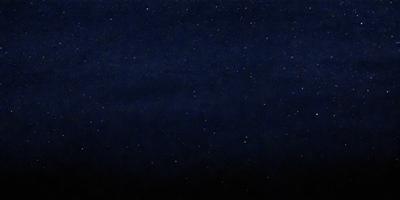 The primary subject of the image is the night sky, which is filled with stars. The setting is a dark, star-filled sky, and the visual style is a photo. The colors and mood of the image are predominantly dark and serene, with the stars providing a sense of wonder and tranquility.