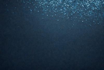 The primary subject of the image is a blue background with a pattern of blue dots. The setting is a dark blue background, which creates a contrast with the blue dots. The visual style is a digital art or illustration, as the dots are arranged in a visually appealing manner. The colors and mood of the image are predominantly dark and moody, with the blue dots providing a touch of brightness and contrast.