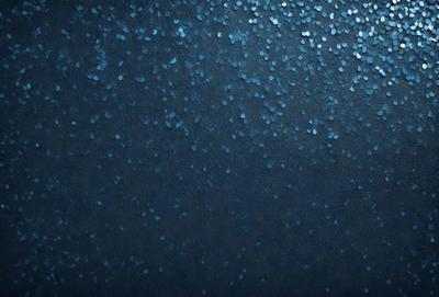 The primary subject of the image is a blue background with a pattern of blue and white glittery dots. The setting is a dark blue background, which contrasts with the glittery dots. The visual style is a digital art or illustration, as the glittery dots are created through a digital medium. The colors and mood of the image are predominantly dark blue and glittery, creating a sense of depth and intrigue.