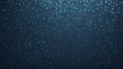 The primary subject of the image is a blue background with a pattern of blue and white specks. The setting appears to be a dark, possibly underwater, environment. The visual style of the image is a close-up of the blue and white speck pattern, creating a unique and intriguing appearance. The colors and mood of the image are predominantly dark and moody, with the blue and white specks adding a touch of brightness and contrast.