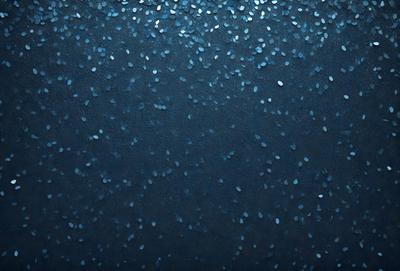 The primary subject of the image is a blue background with a pattern of blue glitter or sequins. The setting is a dark background, which contrasts with the blue glitter. The visual style is a close-up of the blue glitter pattern, showcasing the intricate details of the sequins. The colors and mood of the image are predominantly blue, with a touch of glittery sparkle, creating a visually appealing and serene atmosphere.