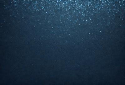 The primary subject of the image is a blue background with a pattern of blue dots. The setting is a dark blue background, which creates a moody atmosphere. The visual style is a close-up of the blue background, showcasing the intricate pattern of blue dots. The colors and mood of the image are predominantly dark and mysterious, with the blue dots adding a touch of visual interest.