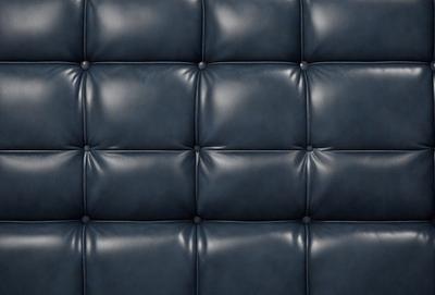 The primary subject of the image is a blue leather couch. The setting is a room with a blue wall, and the visual style is a close-up of the couch. The colors and mood of the image are predominantly blue, creating a calm and relaxing atmosphere.