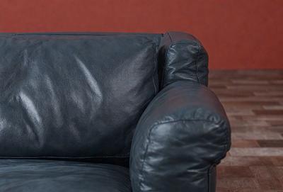 The primary subject of the image is a black leather couch. The setting is a room with a red wall in the background. The visual style is a photo, and the dominant colors are black and red. The overall atmosphere is modern and stylish.