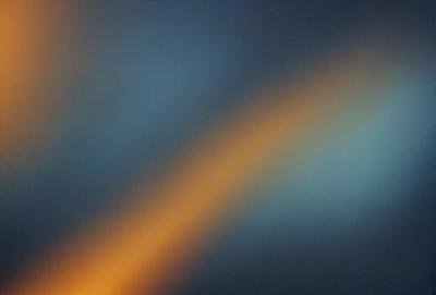 The primary subject of the image is a brightly colored, rainbow-like light, which appears to be a sunset or sunrise. The setting is a dark, cloudy sky, creating a dramatic contrast with the vibrant light. The visual style of the image is a combination of photo and digital art, as it captures the natural beauty of the sunset or sunrise while also showcasing the artist's creativity in blending colors and patterns. The colors and mood of the image are pre