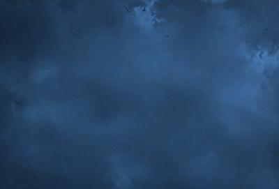 The primary subject of the image is a cloudy blue sky. The setting is an open sky, with no visible land or buildings. The visual style is a natural, outdoor scene. The dominant colors are blue and gray, creating a calm and serene atmosphere.
