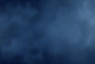 The primary subject of the image is a cloudy blue sky. The setting is a dark, cloudy sky, which creates a moody atmosphere. The visual style is a photo, capturing the natural beauty of the cloudy sky. The colors and mood of the image are predominantly dark and cloudy, with the blue hue of the sky providing a contrasting element.