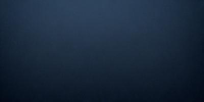The primary subject of the image is a large, dark blue surface. The setting is a vast, empty space with no visible objects or backdrop. The visual style is a close-up of the dark blue surface, which gives the image a moody and dramatic atmosphere.