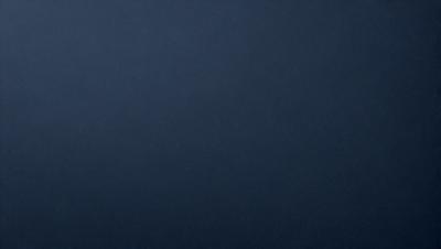 The primary subject of the image is a large, dark blue surface. The setting is a vast, empty space with no visible objects or backdrop. The visual style is a simple, monochromatic design. The colors and mood are predominantly dark and moody, with the blue surface creating a sense of depth and mystery.