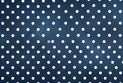 The primary subject of the image is a pattern of white dots on a blue background. The setting is a dark blue surface, which contrasts with the white dots. The visual style is a combination of a photo and a digital art, as the dots are arranged in a way that resembles a digital artwork. The colors and mood of the image are predominantly dark blue and white, creating a calm and serene atmosphere.
