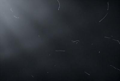 The primary subject of the image is a cloudy sky. The setting is a dark, cloudy night with a few streaks of light. The visual style is a black and white photo, giving it a classic and timeless appearance. The colors and mood of the image are predominantly dark and moody, with the cloudy sky creating a dramatic atmosphere.