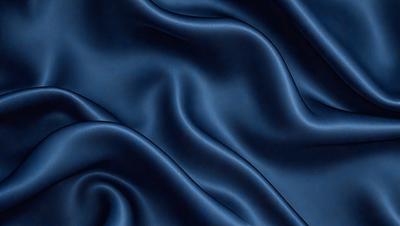 The primary subject of the image is a blue fabric, which appears to be a piece of silk. The setting is a dark background, which contrasts with the blue fabric. The visual style is a close-up of the fabric, showcasing its texture and details. The colors and mood of the image are predominantly blue, creating a calm and serene atmosphere.