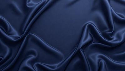 The primary subject of the image is a blue fabric, which appears to be a piece of silk. The setting is a dark room, and the visual style is a close-up of the fabric. The colors and mood of the image are predominantly dark and moody, with the blue fabric being the main focus.