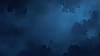 The primary subject of the image is a cloudy blue sky. The setting is a dark blue background, which creates a moody atmosphere. The visual style is a photo, capturing the beauty of the cloudy sky. The colors and mood are predominantly dark blue and somewhat gloomy, with the clouds adding a sense of depth and intrigue to the scene.