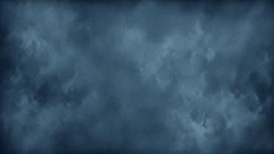 The primary subject of the image is a cloudy sky. The setting is a dark, cloudy day with a blue background. The visual style is a photo of the sky, showcasing the clouds and their patterns. The colors and mood of the image are dark and moody, with the clouds creating a dramatic atmosphere.