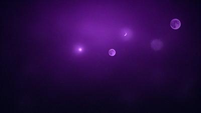 The primary subject of the image is a purple sky with a moon and a few stars visible. The setting is a nighttime sky, and the visual style appears to be a photo. The colors and mood of the image are predominantly purple, creating a serene and peaceful atmosphere.