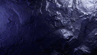 The primary subject of the image is a close-up of a black, textured surface. The setting appears to be a dark room, with the surface possibly being a piece of fabric or a wall. The visual style of the image is a close-up, which emphasizes the texture and details of the surface. The colors in the image are predominantly black, creating a moody and dramatic atmosphere.