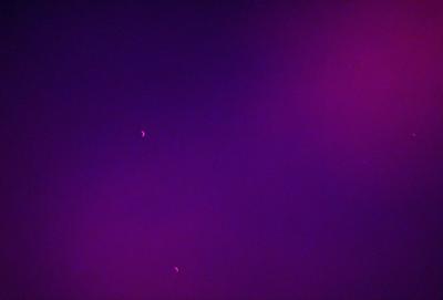The image features a purple sky with two small, bright objects in the foreground. The sky appears to be a deep shade of purple, creating a striking contrast with the objects. The objects are positioned close to each other, and their presence adds a sense of depth and interest to the scene. The overall atmosphere of the image is serene and captivating.