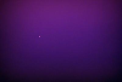 The primary subject of the image is a single star, which is located in the middle of the purple sky. The setting is a vast, dark purple sky, which serves as the backdrop for the star. The visual style of the image is a photo, capturing the star and its surroundings. The colors and mood of the image are predominantly purple, creating a serene and peaceful atmosphere.