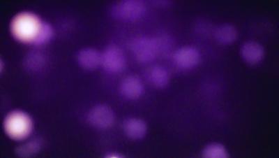 The image is a purple background with a pattern of white dots. The dots are arranged in a circular pattern, creating a visually interesting and unique design. The primary subject of the image is the pattern of white dots, which are the main focus and draw attention to the overall composition. The setting or background is a purple surface, which complements the white dots and adds depth to the image. The visual style of the image is a combination of artistic design and digital art, as the white dots are created through