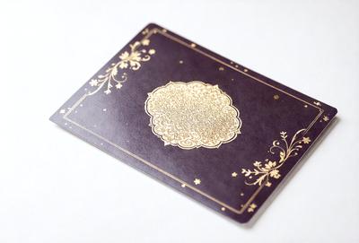 The primary subject of the image is a decorative book or album cover with a gold design. The setting is a white background, which provides a clean and uncluttered look. The visual style is a combination of digital art and illustration, as the gold design and intricate patterns are created using digital tools. The colors and mood of the image are predominantly gold and elegant, giving the impression of a luxurious and sophisticated item.
