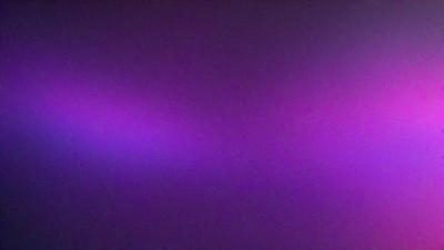 The primary subject of the image is a purple wall. The setting is a dark room, and the visual style appears to be a photo. The dominant colors are purple and black, creating a moody atmosphere.