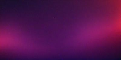 The primary subject of the image is a star, which is located in the middle of the purple sky. The setting is a dark, purple background, which creates a dramatic and moody atmosphere. The visual style of the image is a photo, capturing the star and its surroundings. The colors and mood of the image are predominantly purple, with the star being the main focal point against the dark, purple sky.