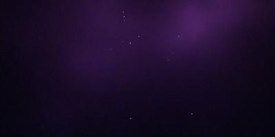 The image features a purple sky with a few stars scattered throughout the scene. The primary subject is the night sky, which is the setting and background of the image. The visual style is a combination of a photo and digital art, creating a unique and artistic representation of the night sky. The colors and mood of the image are predominantly purple, giving it a serene and peaceful atmosphere.