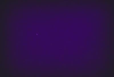 The image is a purple night sky with a single star visible in the distance. The star is located towards the left side of the image, and the rest of the sky is dark and void of any other celestial objects. The purple hue of the sky creates a serene and peaceful atmosphere.