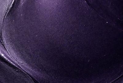 The primary subject of the image is a purple surface, which appears to be a piece of fabric or a wall. The setting is a dark room, and the visual style is a close-up of the purple surface. The colors and mood of the image are predominantly purple, creating a calm and serene atmosphere.