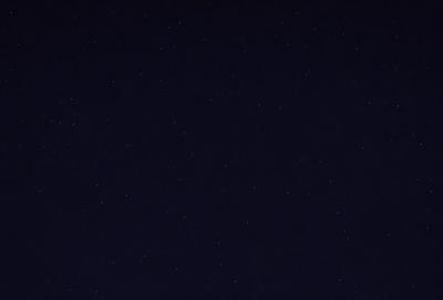 The primary subject of the image is the night sky, which is filled with a multitude of stars. The setting is a dark, star-filled night, with no visible landmarks or other objects. The visual style is a natural, nighttime scene, with the stars being the main focus. The colors and mood of the image are predominantly dark and serene, with the stars providing a sense of wonder and tranquility.