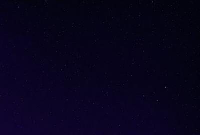 The primary subject of the image is the night sky, which is filled with stars. The setting is a dark, star-filled sky, and the visual style is a photo of the night sky. The colors and mood of the image are predominantly dark and serene, with the stars providing a sense of wonder and tranquility.