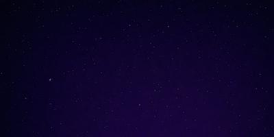 The primary subject of the image is the night sky, which is filled with stars. The setting is a dark, star-filled sky, and the visual style is a photo. The colors and mood of the image are predominantly dark and moody, with the stars being the main source of light in the scene.