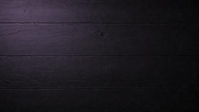 The primary subject of the image is a wooden wall with a black leather-like texture. The setting is a dark room, and the visual style appears to be a close-up of the wooden wall. The colors and mood of the image are predominantly dark, with the black leather-like texture creating a moody atmosphere.